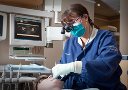 A staff member cleaning a patient's teeth